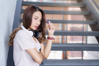 Genç öğrenci erkek merdiven Kampüs alanında kulaklık ile oturmak