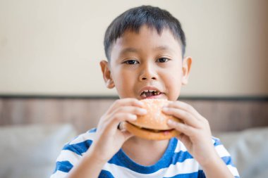mutlu Asyalı çocuk restoranda hamburger yemek
