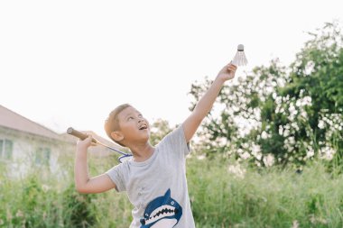 Asyalı çocuk çocuk günbatımı açık Badminton oynuyor