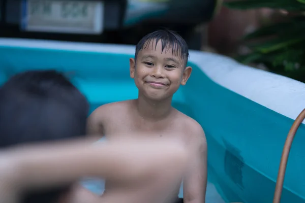 Menino asiático jogar água na piscina inflável — Fotografia de Stock