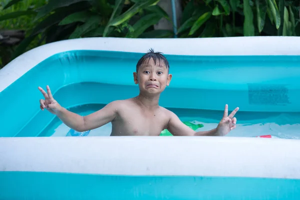 Menino asiático jogar água na piscina inflável — Fotografia de Stock