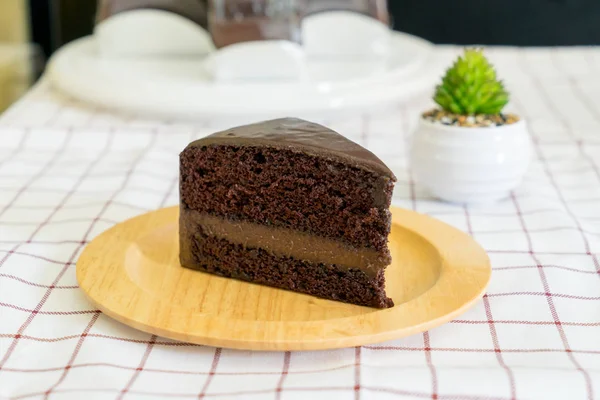 Un trozo de delicioso pastel de chocolate en un plato de madera — Foto de Stock
