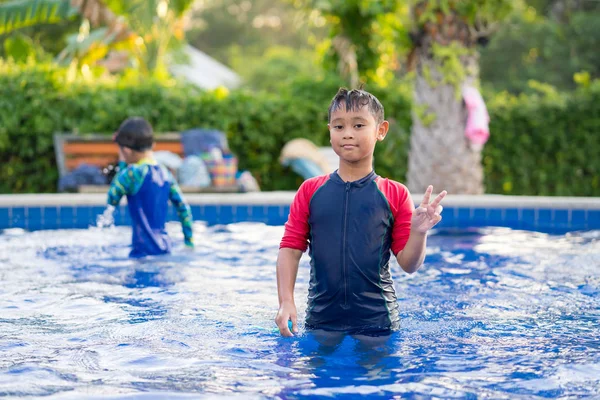 Menino asiático feliz nadando na piscina no verão Fotografia De Stock