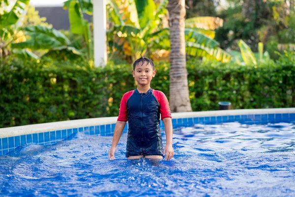 Menino asiático feliz nadando na piscina no verão Imagem De Stock