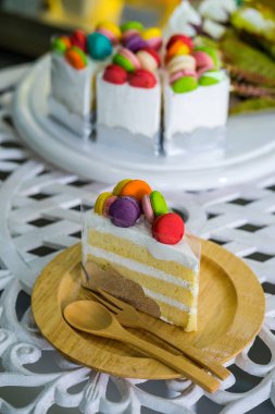 Üzerine makarna ile süslenmiş kremalı pasta, tahta bir tabağa yerleştirilir