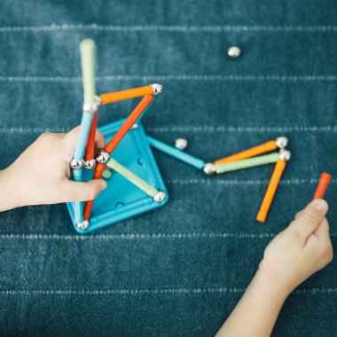 Çocuk evde manyetik sopa oyunuyla oynuyor. Anaokulu çocuğu oynarken geometrik şekiller öğreniyor. Evde eğlenceli aile aktiviteleri..