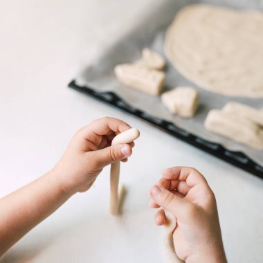 Küçük beyaz çocuk mutfak masasında tuzlu hamur ile oynuyor. El yapımı sıfır bel yapımı oyuncaklar yapmak için DIY kilini modelleyen eller. Eğlenceli ve yaratıcı bir aile aktivitesi. Evde eğitim projesi.