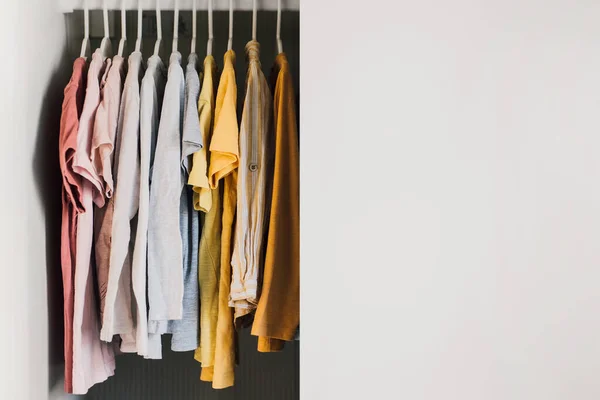 Colorful variety of shirts, t-shirts and blouses on hangers inside a wardrobe. Children apparel for the summer collection. Casual kids fashion, organic cotton clothing. Selective focus.