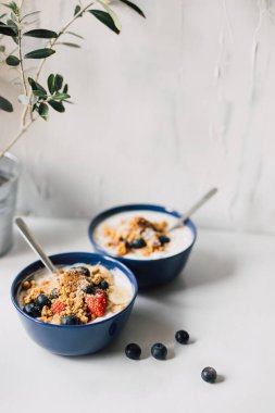 Mısır gevreği, yoğurt, taze çilek ve böğürtlen meyveleri, beyaz masada fotokopi alanı ile. Sabah yemeği için besleyici bir seçim. Sağlıklı bir yaşam tarzı. Seçici odak.