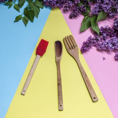 Ahşap mutfak aletleri canlı modern arka planda izole edilmiş taze leylak çiçek çerçeveli dekor. Yemek servisi, şef blog ya da aşçılık okulu sunumu kavramı. Üst manzara, düz uzanma