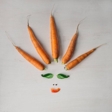 Sebzelerden yapılan yaratıcı kompozisyon: havuç, fesleğen yaprağı, kırmızı biber. Minimum düzlük. Vejetaryen, organik, sağlıklı beslenme konsepti.