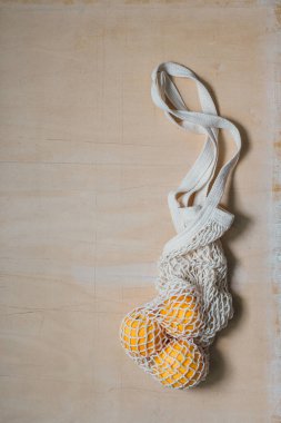 Doğal ahşap kaplama portakallı beyaz çevre dostu ip torbası. Yeniden kullanılabilir ürünler için sorumlu tüketim. Ekolojik, sıfır atık, yeşil ve plastiksiz yaşam tarzı. Düz yatış, üst görünüm.