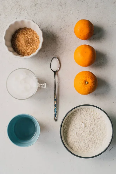 白のキッチンテーブルトップビーガンデザートレシピ成分 小麦粉 ココナッツオイル 水とオレンジ 柑橘系の果物タルトやフランスのガレット ロワ地殻を作るプロセス — ストック写真