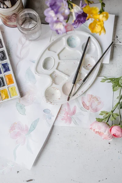 用白纸上的彩绘花卉和包括水彩画和画笔在内的艺术品进行艺术化的模仿 画家的工作空间 或画家使用的白色桌子 顶部视图 — 图库照片