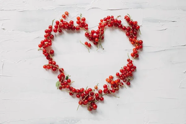 心形的设计来自新鲜采摘的红醋栗 在白色的红色浆果的复制空间下 最小的平面布局组成 健康的生活方式支持当地农民的概念 富含维生素的美味的夏季有机水果 图库图片