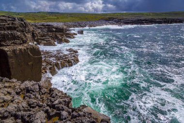 Fırtınalı deniz ve dalgalar kayalara çarpıyor taş arazide Burren, County Clare, İrlanda