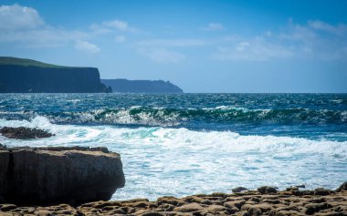 Doolin sahilinde dalgalar Moher, County Clare, İrlanda 'nın muhteşem uçurumlarına bakıyor.
