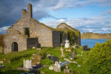 Schull, West Cork, County Cork, İrlanda 'da denizin arka planındaki eski taş kilise.