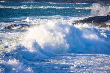 Ocean waves breaking on stone coast in Ireland clipart