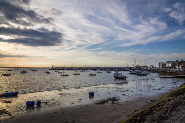 Gün batımında kayalık deniz kıyısında tekneleri olan liman.