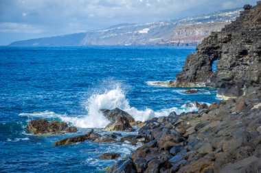 Tenerife, Canaria Adaları, İspanya 'da Puerto de la Cruz' daki Martianez Körfezi yakınlarındaki kayalıklardaki Atlantik kırıklarından gelen dalgalar taşlara çarpıyor.