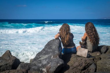 İspanya, Canaria Adaları, Tenerife 'de Puerto de la Cruz sahilinde konuşan ve dinlenen iki kadın