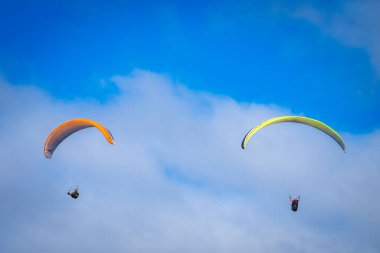 Mavi gökyüzünde paraşütle atlayan insanlar 