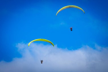 Mavi gökyüzünde paraşütle atlayan insanlar