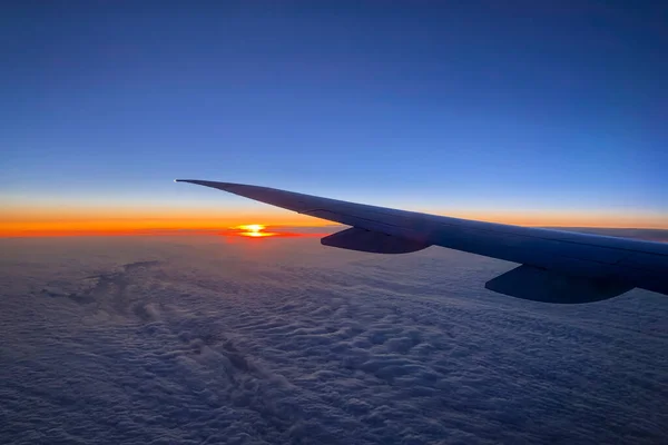 Aerial view from airplane on cloudy sky at sunset time