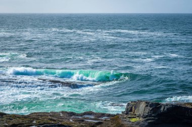 İrlanda 'da taştan kıyılarda okyanus dalgaları kırılıyor