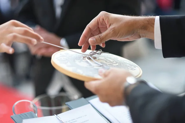 Hands untying wedding rings from circular frame.