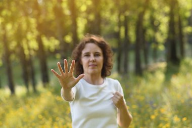 Ormanda egzersiz yapan bir kadın seçici bir şekilde eline odaklanmış..