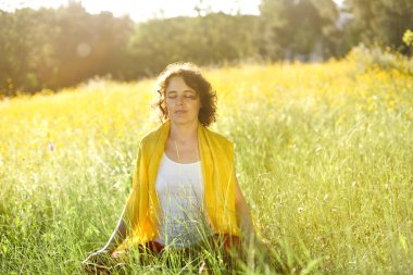 Gün batımında kır çiçekleri arasında güzel meditasyon..