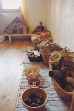 Waldorf pedagojisinden tahta oyuncaklarla dolu sepetler ve ahşap bir ev..