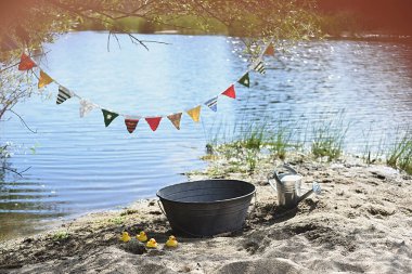 Renkli bayraklar, antika kase, sulama tenekesi ve plastik ördekler gibi dekoratif nesnelerle donatılmış fotoğraflar..