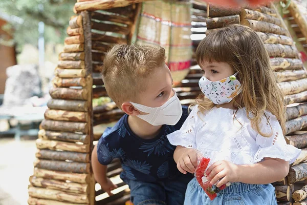 Küçük çocuklar birbirlerinin gözlerinin içine bakıp maske takıyorlar..