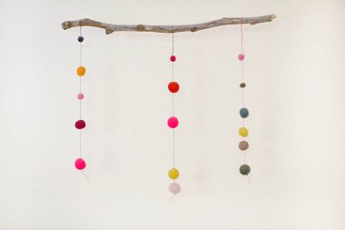 Ahşap ve renkli yün gibi doğal malzemelerden yapılmış asılı cep telefonu.