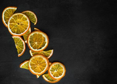 Sağlıklı atıştırmalıklar. Siyah arka planda portakal aromalı meyve cipsi. Siyah dokuda kurutulmuş portakal dilimleri. Dekorasyon için turunçgil dilimleri. 