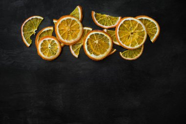 Siyah arka planda portakal aromalı meyve cipsi. Siyah dokuda kurutulmuş portakal dilimleri. Sağlıklı atıştırmalıklar. Süs için turunçgil dilimleri. Noel arkaplanı.