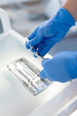 Dişçinin elinde tuttuğu diş hekimi beyaz arka planda lokal anestezi için mavi eldiven taşıma şırıngası izole edilmiş.
