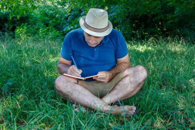 Orta Çağ Adamı Doğada Çimlerde Oturuyor ve Not Defterinde Yazıyor