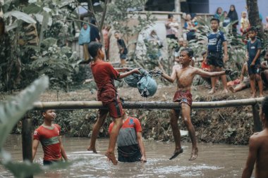 Purbalingga, Endonezya - 13 Ağustos 2018: Çocuklar bağımsızlık gününü kutlamak için göletin üzerinde yastık savaşı yapıyorlar