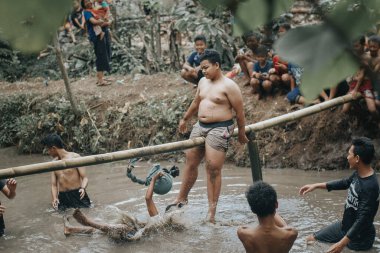 Purbalingga, Endonezya - 13 Ağustos 2018: Çocuklar bağımsızlık gününü kutlamak için göletin üzerinde yastık savaşı yapıyorlar