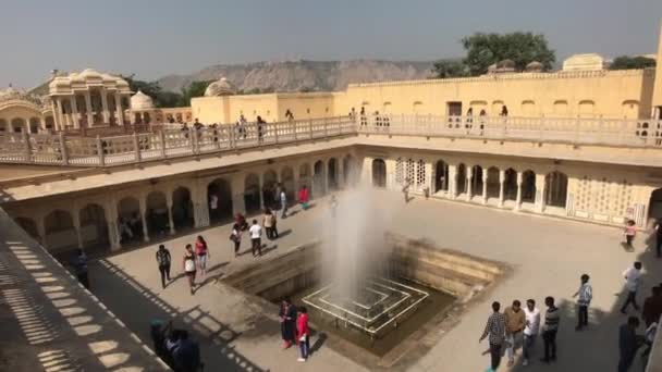 Jaipur, Ινδία - Νοέμβριος 04, 2019: Hawa Mahal τουρίστες με τα πόδια στην πλατεία κοντά στο σιντριβάνι μέρος 5 — Αρχείο Βίντεο