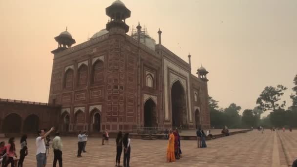 Agra, Indie, 10 listopada 2019, Taj Mahal, turyści robią sobie selfie w tle meczetu — Wideo stockowe
