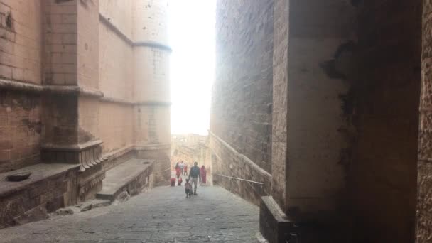 Джодхпур, Индия - 06 ноября 2019 года: туристы из форта Мехрангарх прогуливаются по узкому коридору старой крепости — стоковое видео