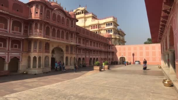 Jaipur, Índia - 04 de novembro de 2019: Os turistas do City Palace caminham contra o pano de fundo de um edifício com paredes cor-de-rosa — Vídeo de Stock