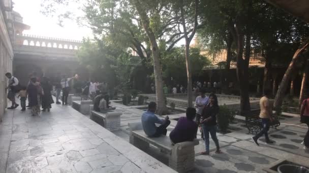 Udaipur, India - 13 de noviembre de 2019: Los turistas del Palacio de la Ciudad se relajan en el patio del edificio histórico — Vídeos de Stock
