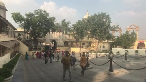 Udaipur, India - 13 de noviembre de 2019: Palacio de la Ciudad Turismo camina por la calle a lo largo de la valla de la antigua fortaleza parte 2 — Vídeos de Stock