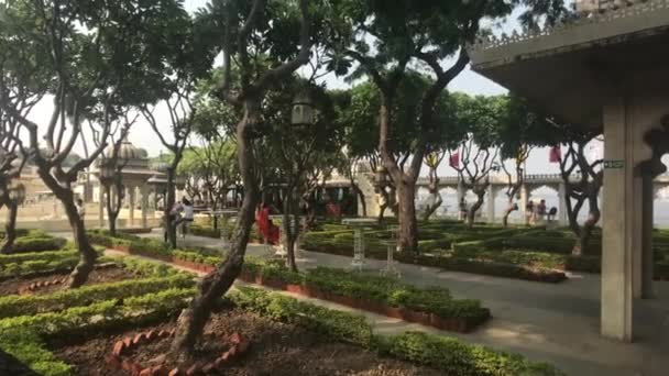Udaipur, India - 12 november 2019: Jag Mandir toeristen staan in de schaduw van bomen — Stockvideo